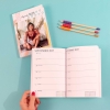 Imprenta de Fotoprix, foto en uso de una mano sujetando una agenda de tapa blanda abierta en los meses de Septiembre y Octubre de  2022.