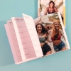 Imprenta de Fotoprix, agenda de tapa blanda abierta en el mes de Julio con una foto en la otra página y otra agenda cerrada en una superficie azul.