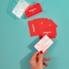 Imprenta de Fotoprix, foto en uso de una mano sujetando una tarjeta de visita de la empresa mientras hay otras colocadas en una superficie azul.