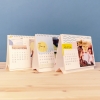 Productos Fotoprix, tres calendarios personalizados con fotos de tamaño 21x15 sobremesa de Fotoprix decorando una mesita de madera.