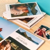 Álbumes de Fotoprix: Foto de varios Fotolibro Plus 21x27 colocados en una mesa de hogar, apreciándose las fotos y los textos de la portada y el grosor.