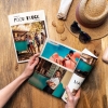Álbumes de Fotoprix. Foto en uso de una Fotorevista 21x27 sujetándola con la mano y doblándose una de las páginas mientras se apoya en una mesa.