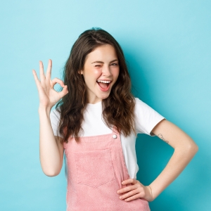 Chica joven sonriendo e indicando con su mano derecha que la garantía de producción Fotoprix le ha funcionado a la perfección.