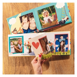 Álbumes Fotoprix. Infantil tapa dura foto en uso pasando página. Álbumes Fotoprix. Infantil de tapa dura, foto en uso pasando una de las páginas apreciándose la flexibilidad de las hojas mientras está en una mesa.