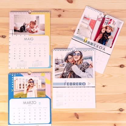 Detalles del calendario Fotoprix: Foto de cuatro calendarios de pared colgados en una maderita, cada uno de un mes y en un idioma diferente.