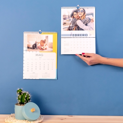 Calendario personalizado de pared Fotoprix, tamaño A4. Calendario de pared Fotoprix,  foto en uso de dos Calendarios personalizados de pared de tamaño A4. En uno se está sujetando por la parte inferior