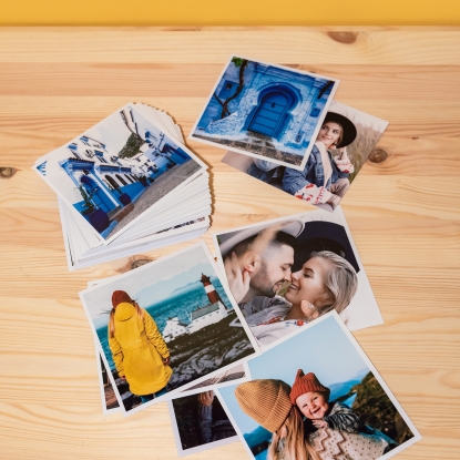Productos de Fotoprix, copias. Foto de varias impresiones a tamaño 13x13 con diferentes bordes y acabados y colocadas en una mesita de madera.