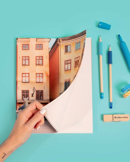 Imprenta de Fotoprix, foto en uso de una mano abriendo un bloc de notas mostrando el contenido de las páginas con cuadrícula para escribir.