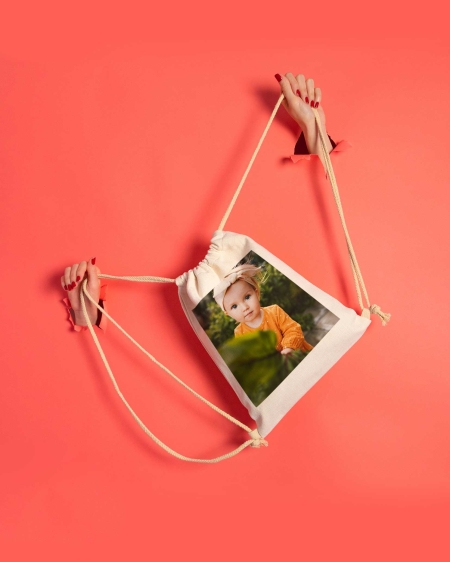 Regalos de Fotoprix, foto en uso sujetando las asas de cuerda de una mochila de lino. Presume de foto especial a cada sitio que vayas. También es un regalo perfecto.