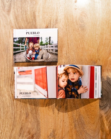 Imagen de 3 álbumes Fotolibro clásico 20x15 cm. sobre una mesa uno abierto  y 2 cerrados mostrando su portada personalizad.