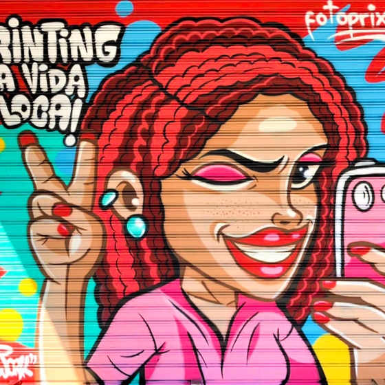 Imagen de la persiana de la tienda de fotografía franquiciada de Fotoprix en Palma de Mallorca.
Donde aparece una joven sonriente con el slogan de la empresa "¡Printing la vida loca!" haciéndose una foto selfie con su teléfono y guiñando un ojo.
