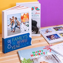 Categoría de Fotoprix, foto de varios álbumes personalizados con fotos colocados en una mesa, unos abiertos y otros cerrados viendo las imagenes y textos.