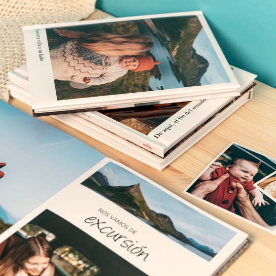 Categoría de Fotoprix, foto de varios álbumes personalizados con fotos colocados en una mesa, unos abiertos y otros cerrados viendo las imagenes y textos.