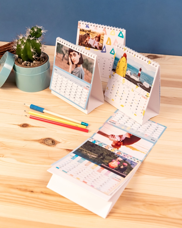 Calendario personalizado con fotos tamaño sobremsa 21x15 de Fotoprix. Foto en uso del calendario pasando página del mes colocado en una mesa.