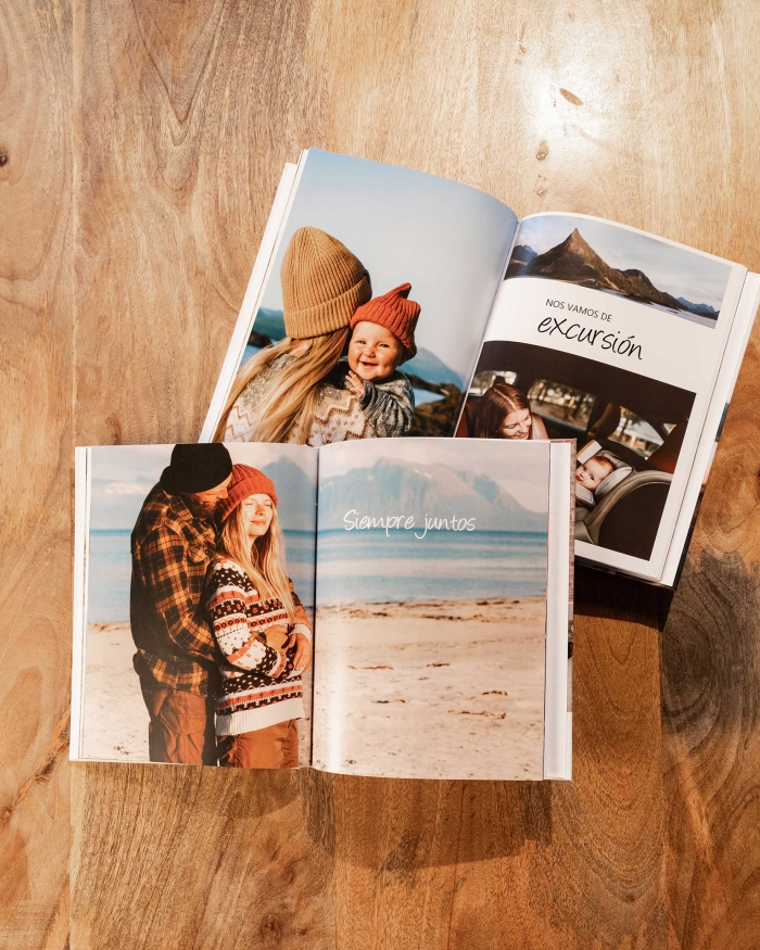 Álbumes de Fotoprix. Foto de dos Fotolibros abiertos con foto a doble página y texto explicativo, colocados en una mesa de casa a modo decorativo.