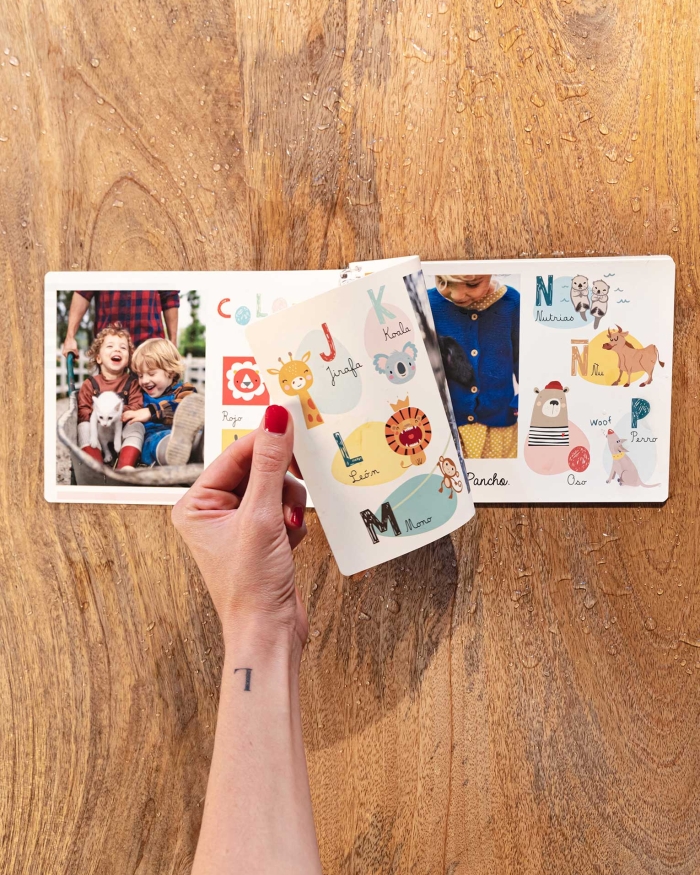 Álbumes Fotoprix. Foto de uso Indestructible 21x27 pasando página. Álbumes de Fotoprix. Foto en uso de un Indestructible 21x27 pasándose una página del álbum mientras está colocado en una mesa del hogar.