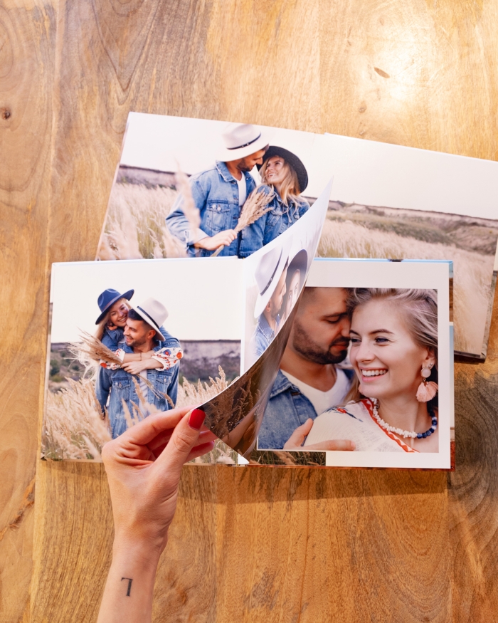 Productos de Fotoprix, foto en uso pasando una hoja de un Álbum Probook mientras está colocado en una mesa junto a otro con foto a doble página.