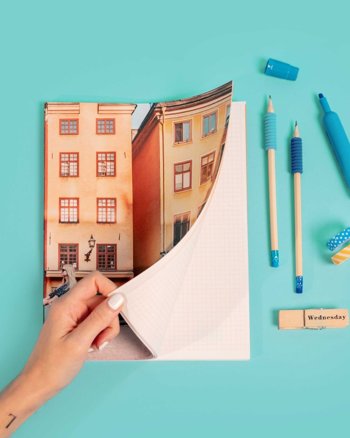 Imprenta de Fotoprix, foto en uso de una mano abriendo un bloc de notas mostrando el contenido de las páginas con cuadrícula para escribir.