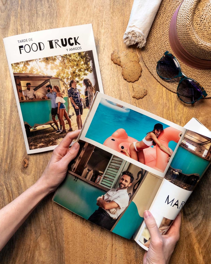 Álbumes de Fotoprix. Foto en uso de una Fotorevista 21x27 sujetándola con la mano y doblándose una de las páginas mientras se apoya en una mesa.